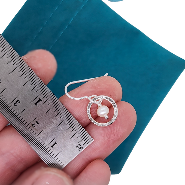 silver circle earrings next to a ruler for scale